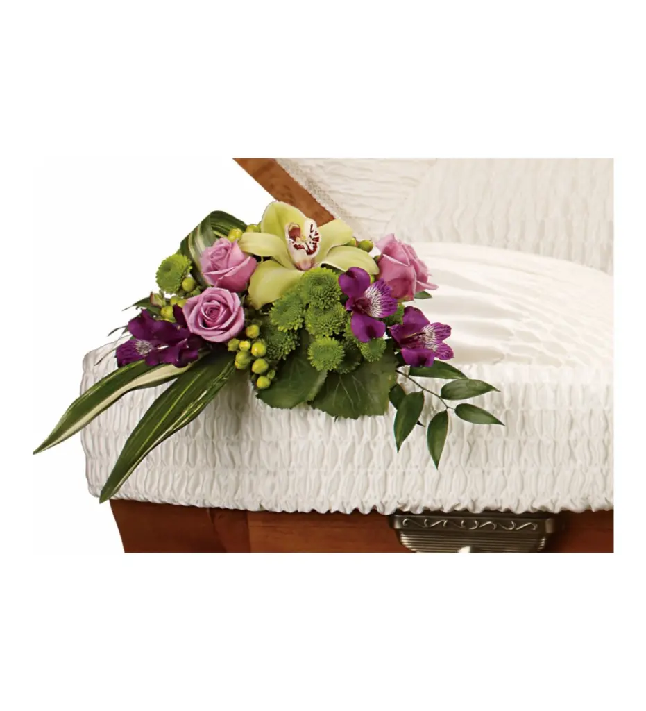 Lavender roses and a green orchid resting on the edge of a casket lining