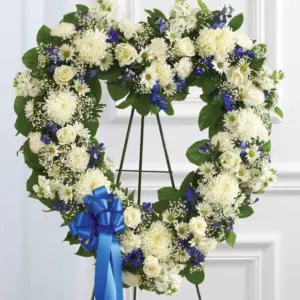 Open blue and white heart of roses and mums on an easel with blue bow