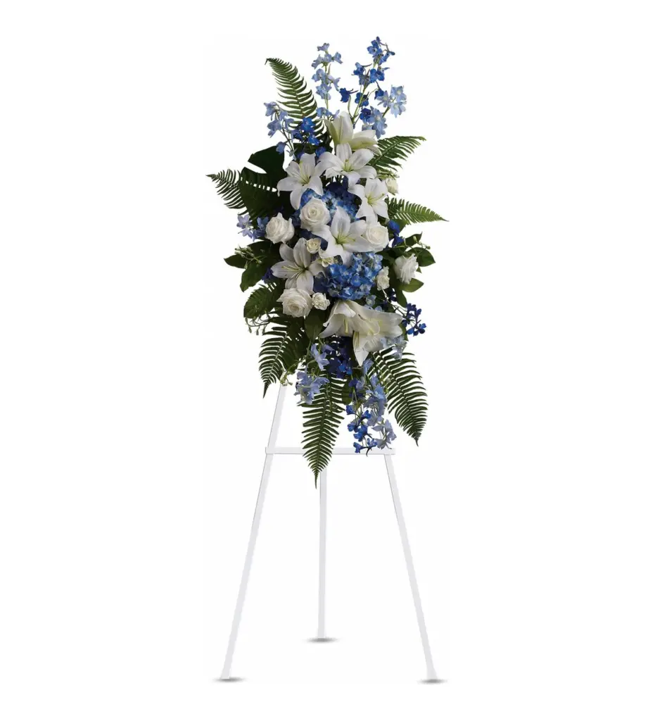 Blue and white standing spray of lilies, roses, hydrangea and delphinium on white easel