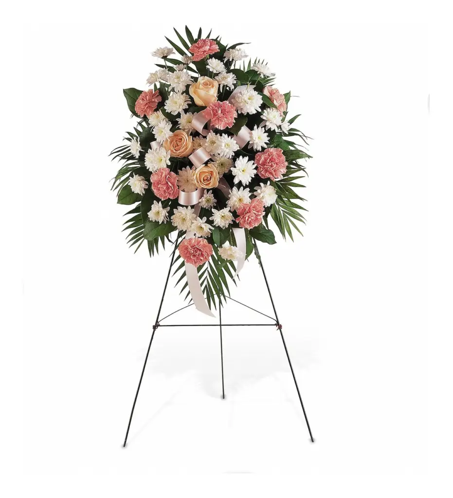 Pink and white standing spray with peach roses and white ribbon on an easel