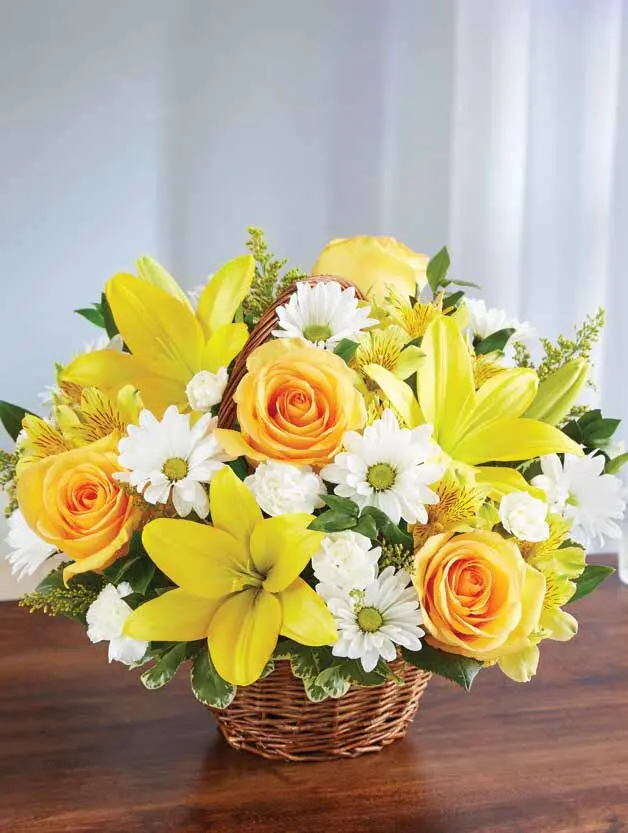 Yellow lilies, roses and white daisies in a small handled wicker basket
