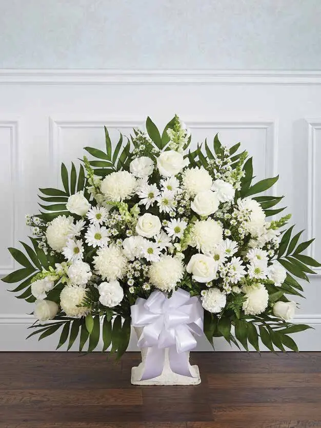 White floor basket of roses, mums and daisies with palm leaves and a white bow