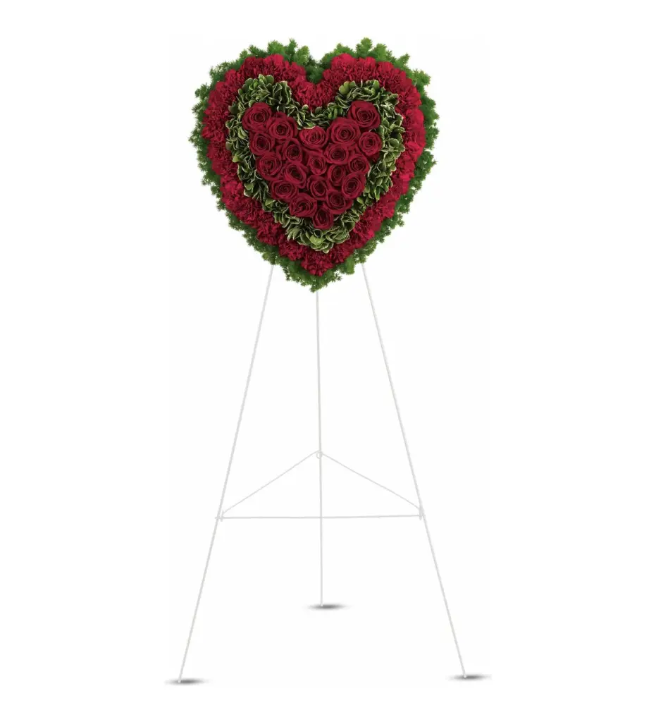 Solid red heart of roses and carnations with green edging on a white easel