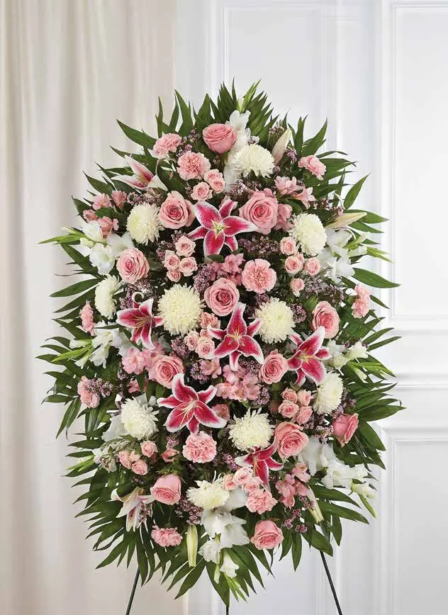 Oval pink and white standing spray of lilies, roses and carnations on an easel
