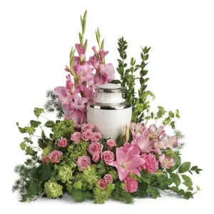 Pink gladiolus, spray roses and lilies around a pearl-white urn with silver trim