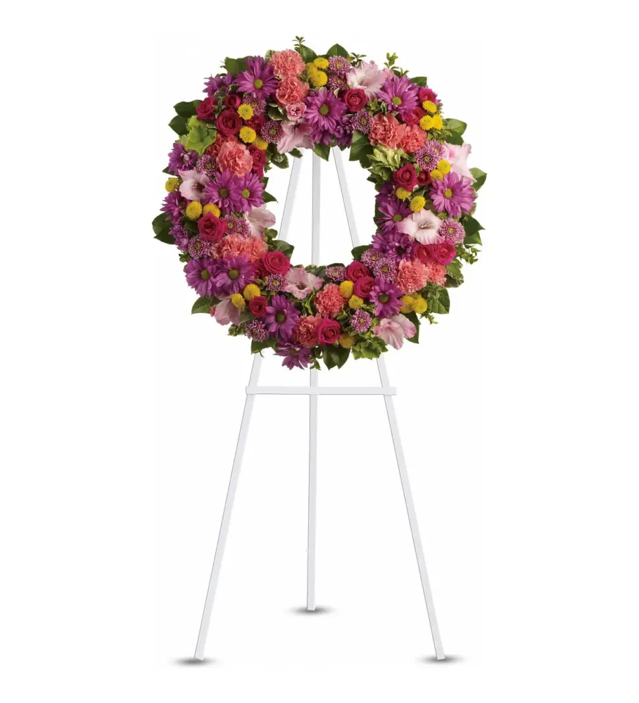 Colorful wreath of purple daisies, pink roses and yellow button mums on an easel