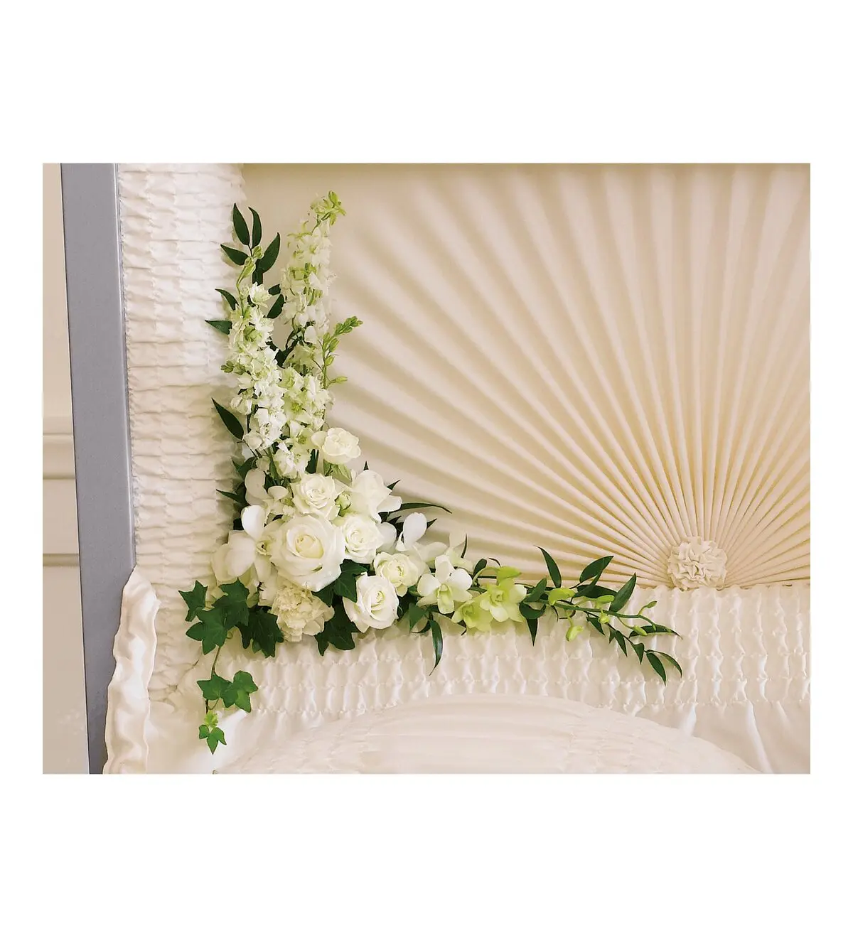 White roses, orchids and larkspur corner piece inside an open casket lid