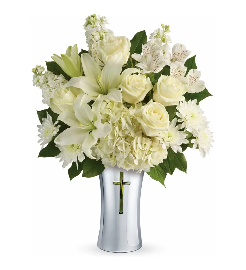 White lilies, roses and hydrangea in a silver vase with a cross cut-out
