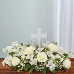 White roses and alstroemeria arranged low around a clear glass cross