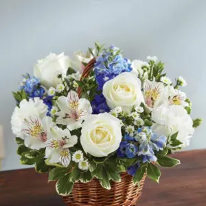 White roses and blue delphinium in a small woven handled basket