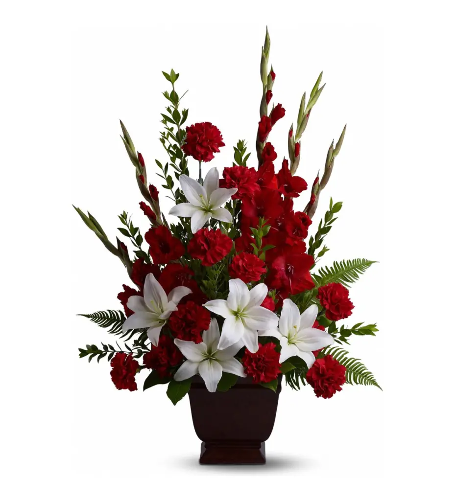 Red gladiolus, red carnations and white lilies in a dark footed container