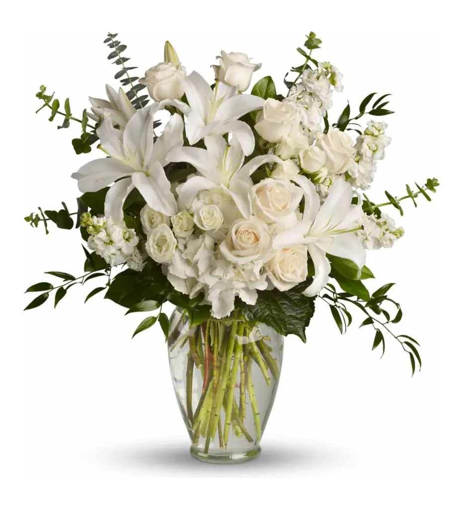 White lilies, roses and hydrangea in a clear glass vase with eucalyptus