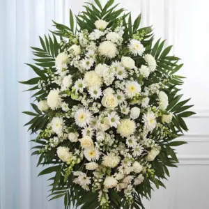 White standing spray of mums, daisies and roses framed with palm leaves on an easel