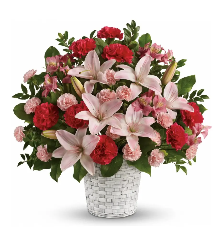 Pink lilies and pink and red carnations in a whitewashed woven basket