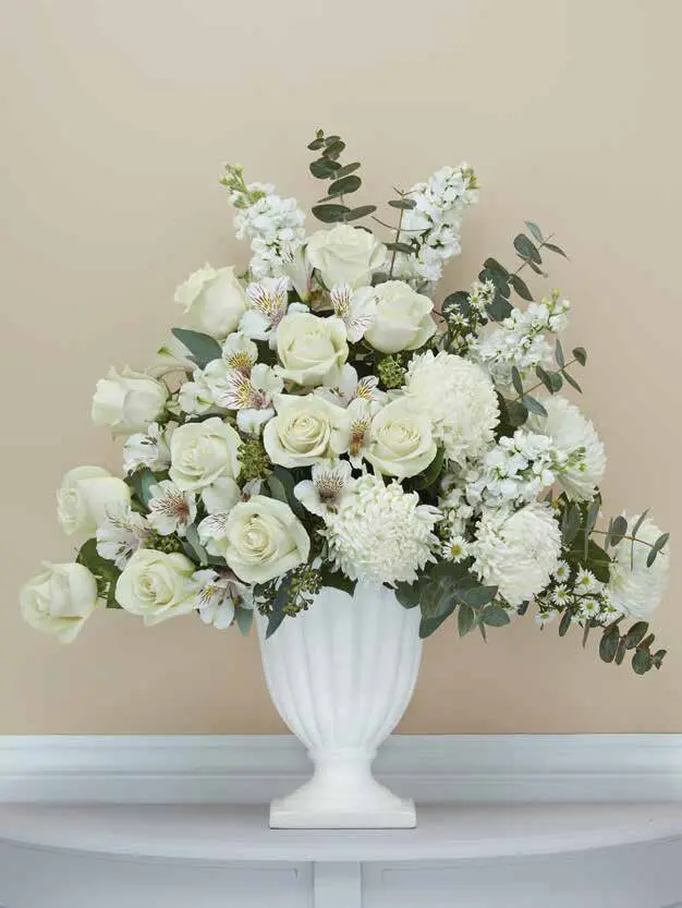 White roses, alstroemeria and mums in a white fluted pedestal vase