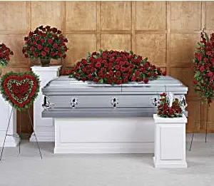 Funeral room with red rose casket spray, heart, standing spray and pedestal arrangements