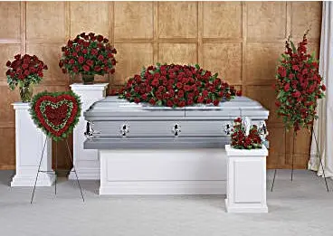 Funeral room with red rose casket spray, heart, standing spray and pedestal arrangements