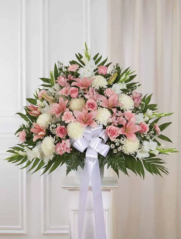 Pink and white floor basket of lilies, roses and mums with white ribbon on pedestal