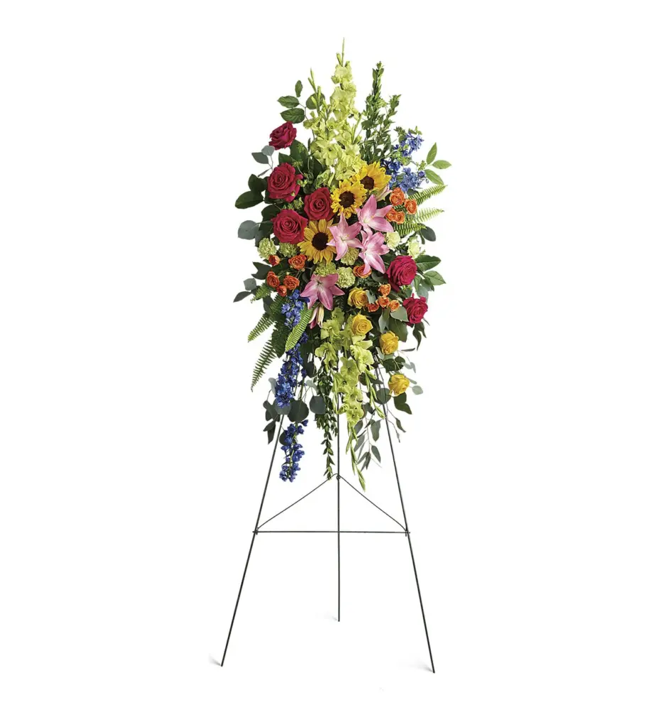Standing spray of pink roses, sunflowers and lilies on a wire easel