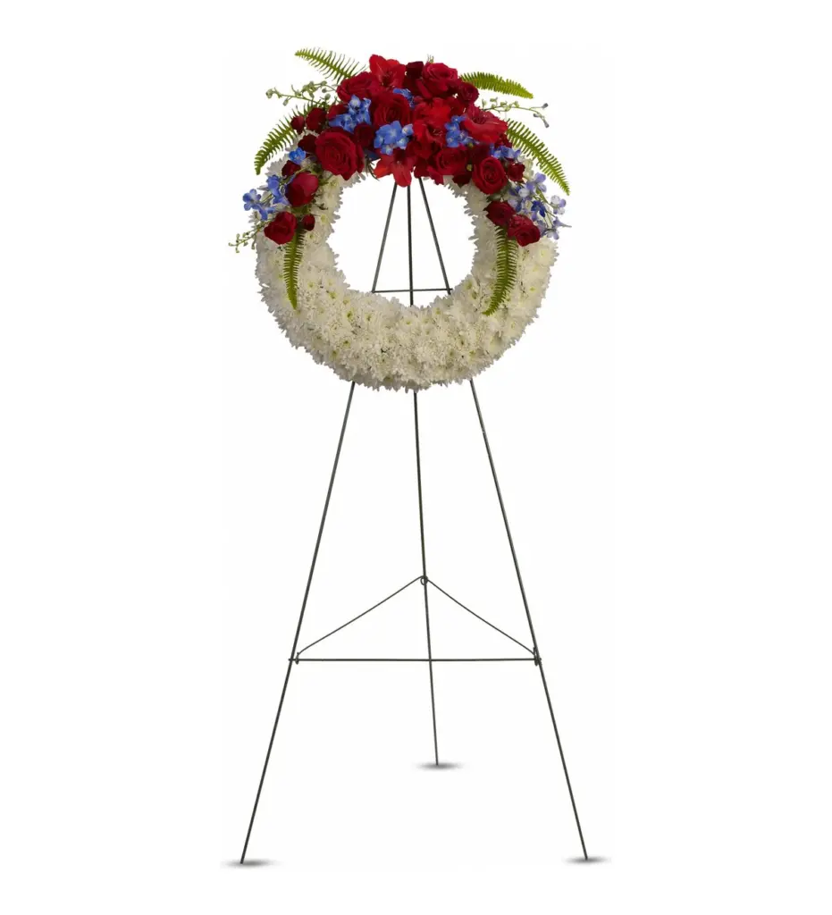 White mum wreath with red roses and blue delphinium on a wire easel