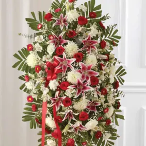 Red roses, pink lilies and white mums in an oval standing spray on an easel