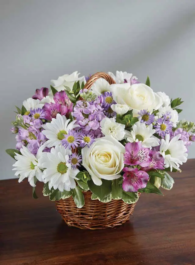 Lavender and white roses, daisies and stock in a small handled wicker basket