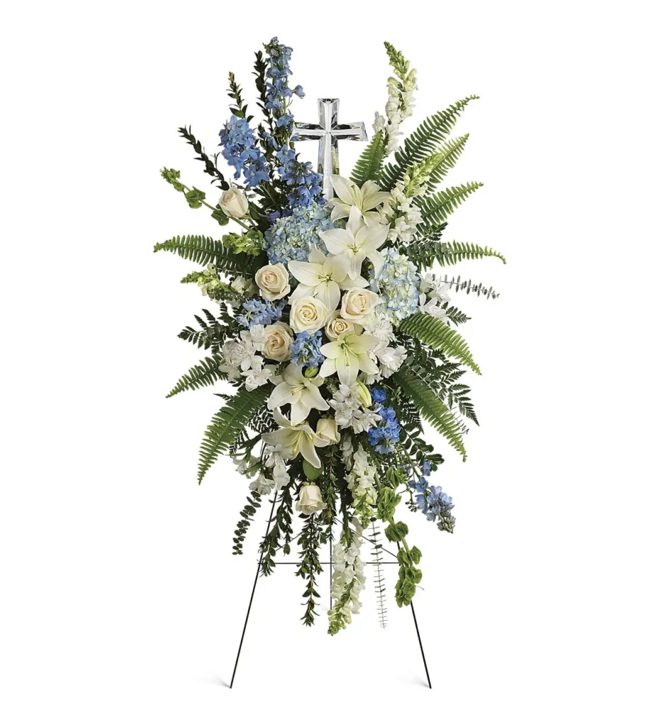 Blue and white standing spray with lilies and a crystal cross on an easel