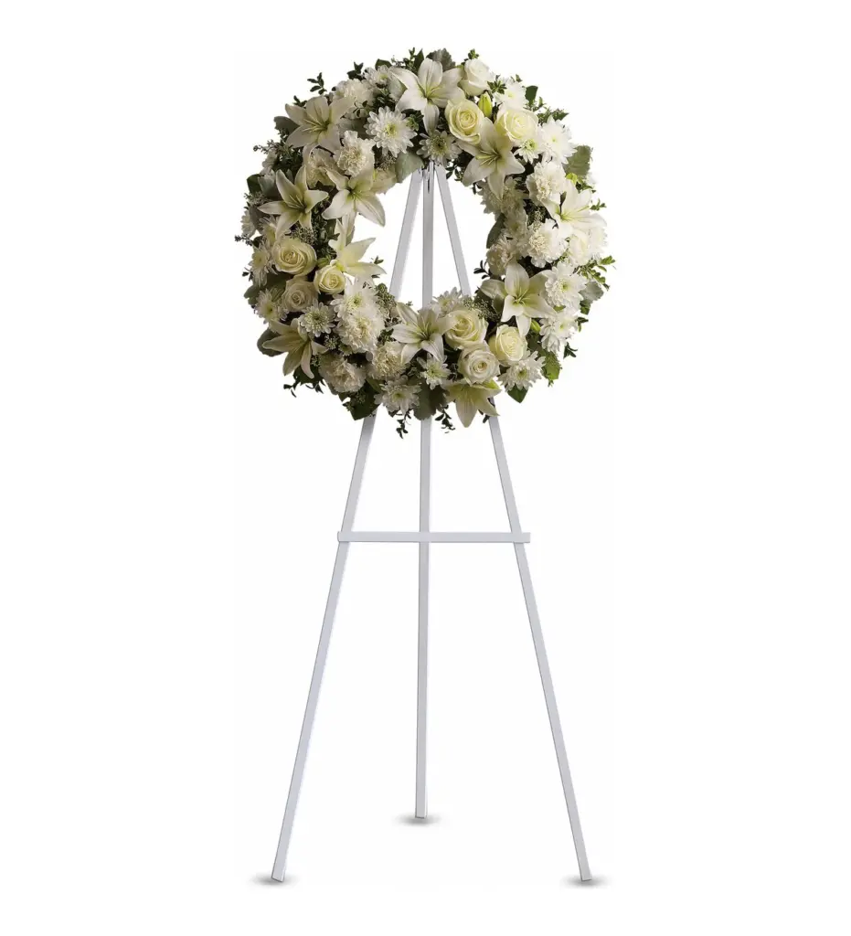White wreath of lilies, roses and carnations on a white wooden easel