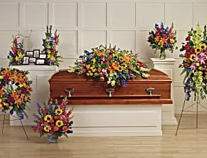 Funeral room with bright multicolor casket spray, wreath, standing spray and arrangements