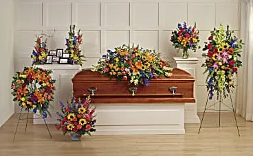 Funeral room with bright multicolor casket spray, wreath, standing spray and arrangements