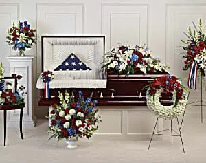 Funeral room with red, white and blue casket spray, wreath, standing spray and arrangements