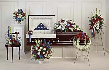 Funeral room with red, white and blue casket spray, wreath, standing spray and arrangements