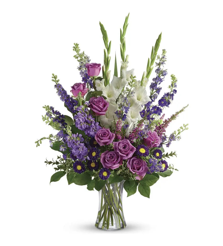 Purple and white flowers in a clear glass vase with roses and gladiolus