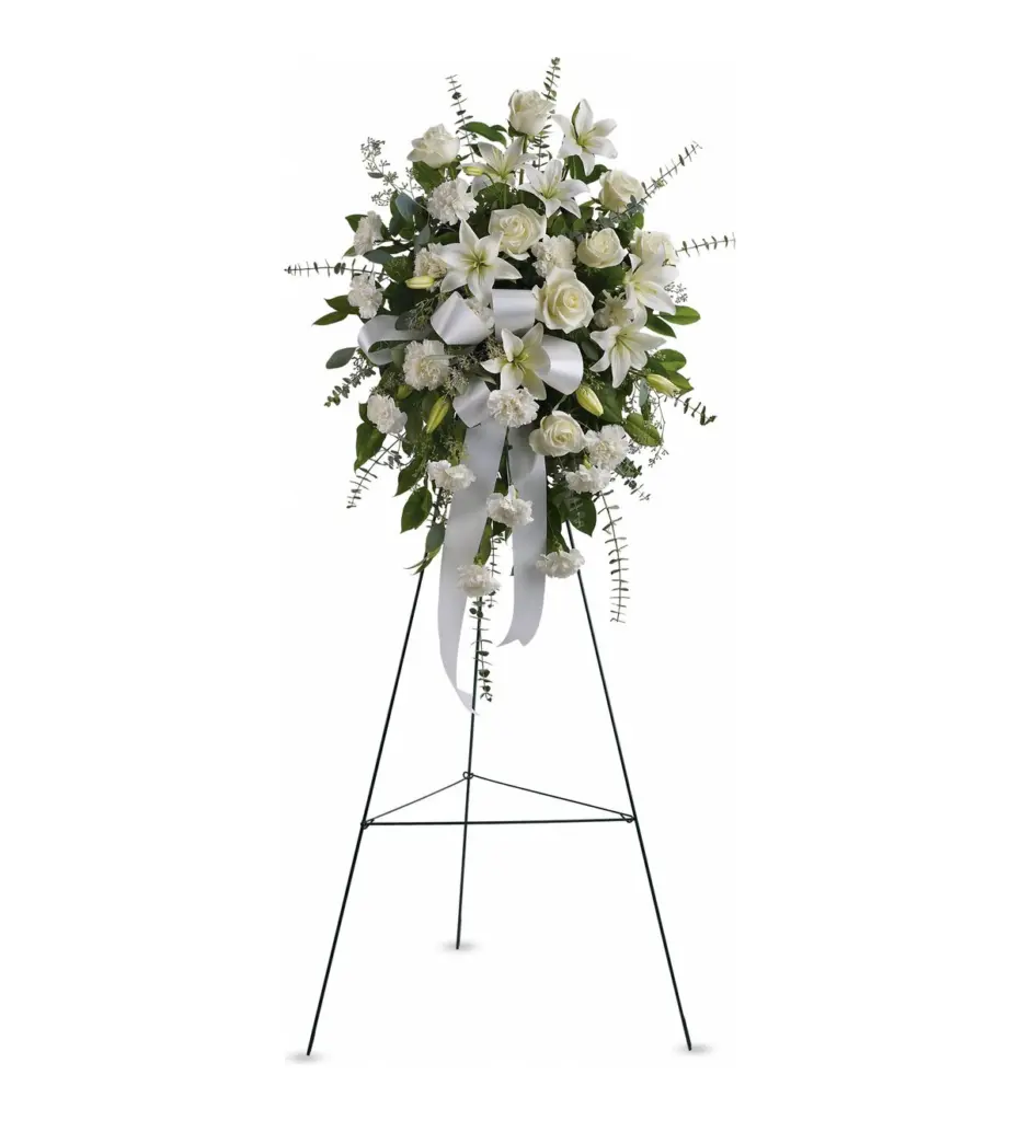 White roses, lilies and carnations standing spray with white ribbon on wire easel
