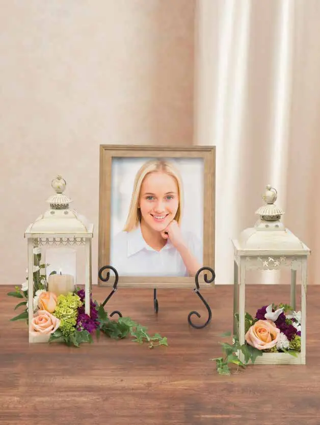 Wooden photo frame on easel between two white lanterns with peach roses