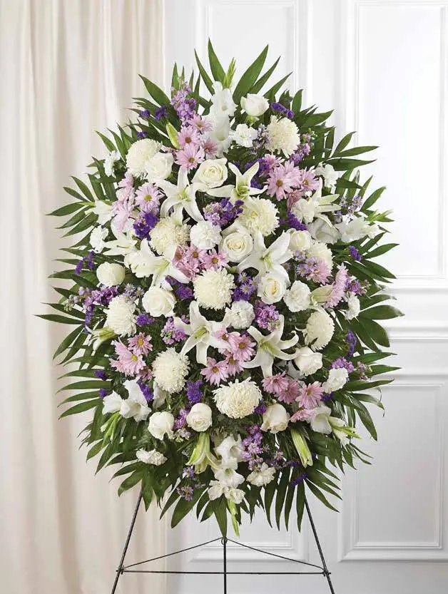 White and lavender oval standing spray of roses and lilies on an easel