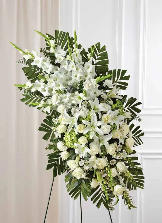 Tall white standing spray of gladiolus, lilies and roses framed with palm