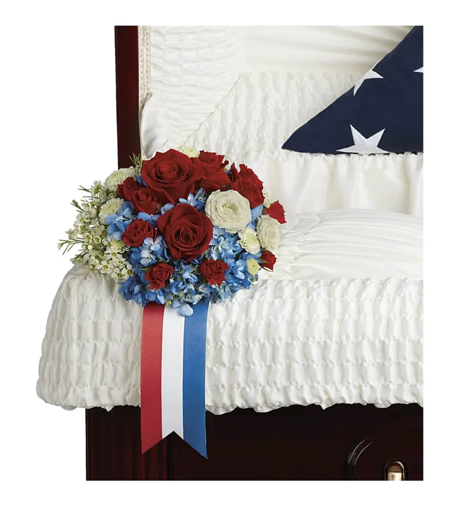 Red roses and blue hydrangea with a red, white and blue ribbon on casket lining