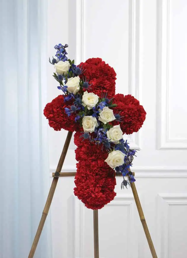 Red carnation cross with white roses and blue delphinium on a wooden easel