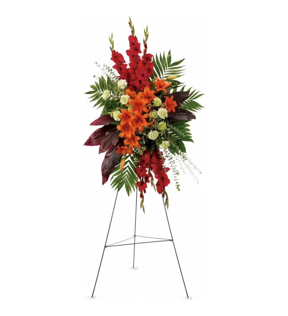 Red gladiolus and orange lilies standing spray with burgundy leaves on easel