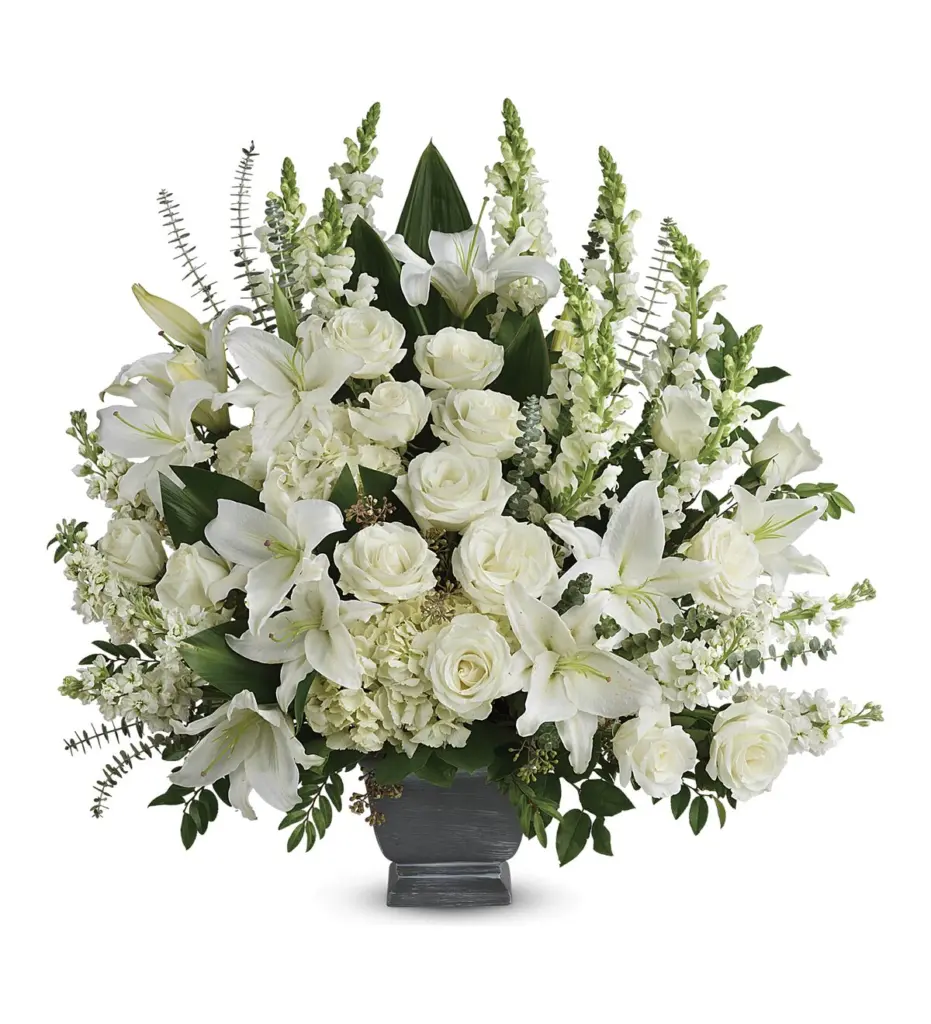 Large white roses, lilies and snapdragons in a gray footed container