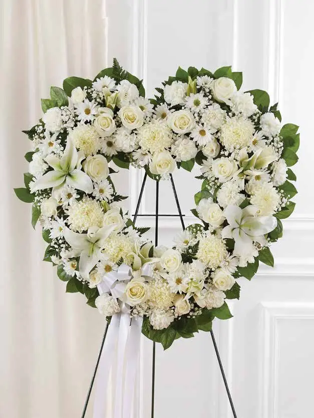 Open white heart of roses and lilies with a white ribbon on an easel