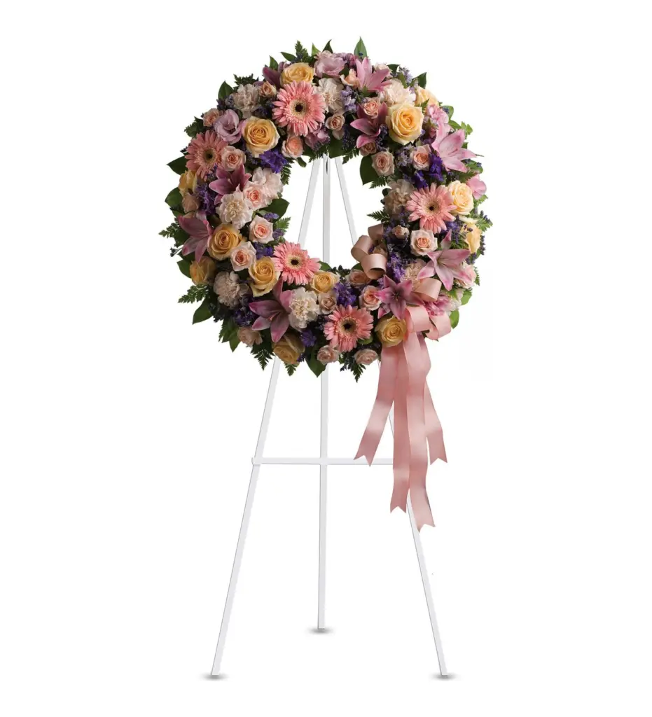 Pastel wreath of peach roses and pink gerberas with a ribbon bow on an easel