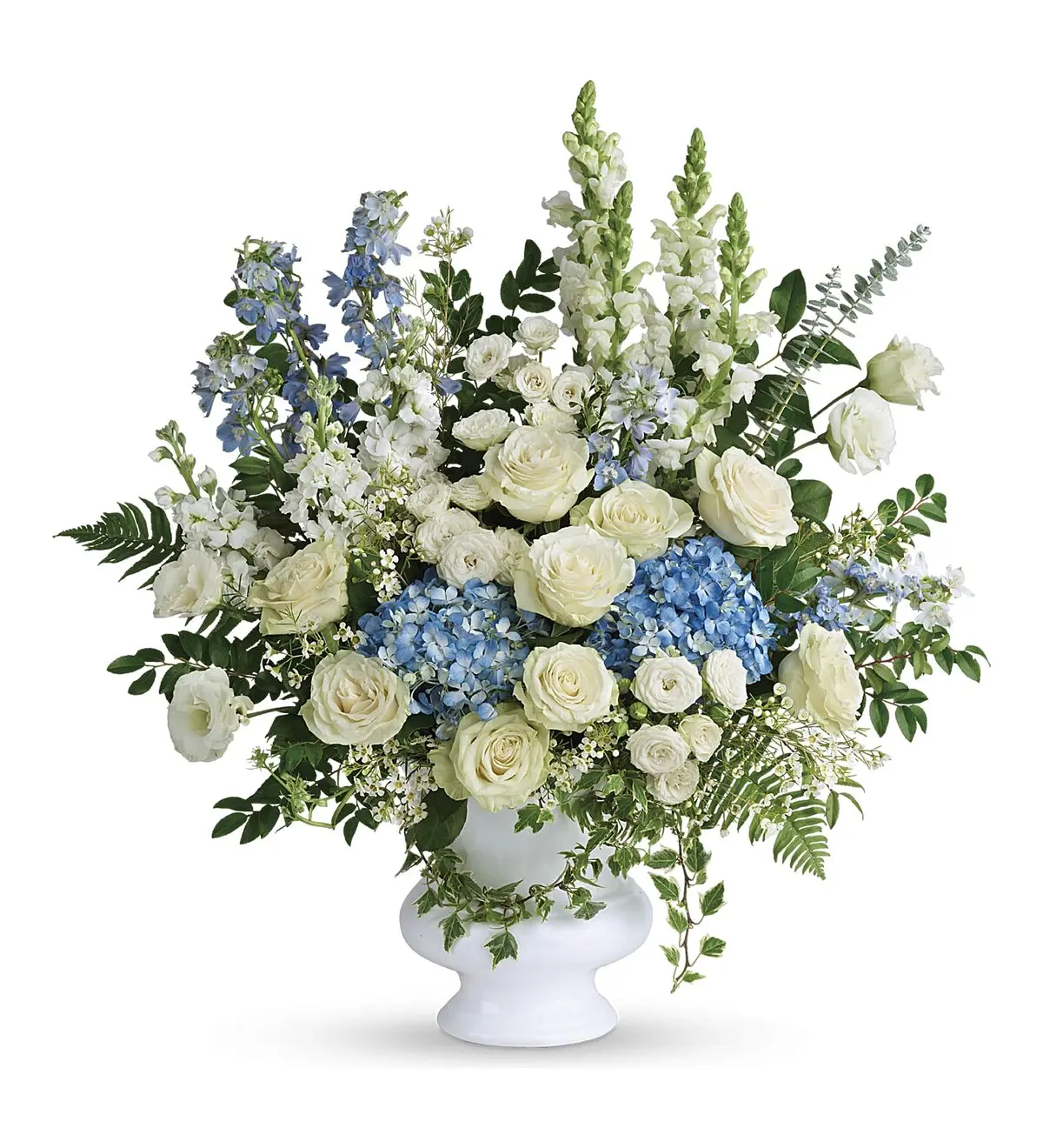 White roses, blue hydrangea and delphinium in a white footed urn container