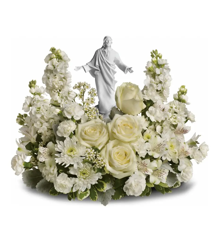 White roses and stock surrounding a white statue of Christ with open arms