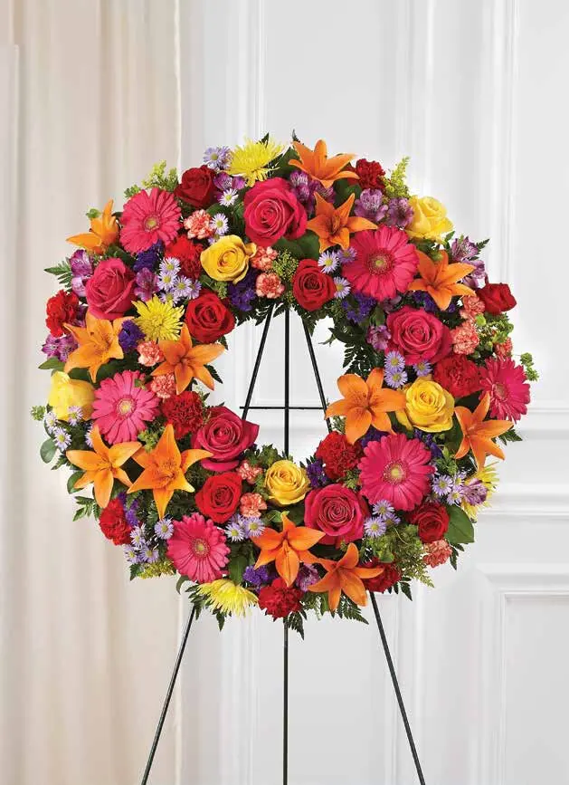 Round standing wreath of pink roses, orange lilies and gerbera daisies on an easel