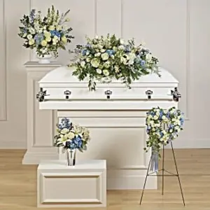 Funeral room with blue and white casket spray, easel piece and vase arrangements