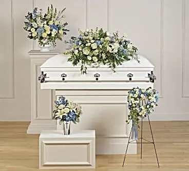 Funeral room with blue and white casket spray, easel piece and vase arrangements