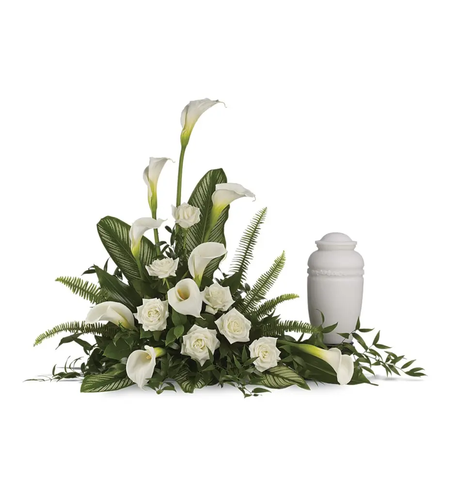 Low white calla lily and rose arrangement beside a plain white cremation urn