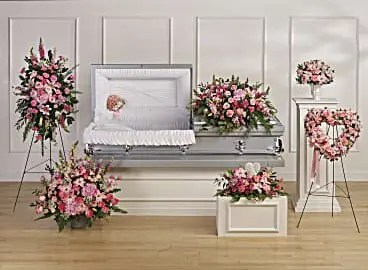 Funeral room with pink casket spray, standing spray, heart and matching arrangements